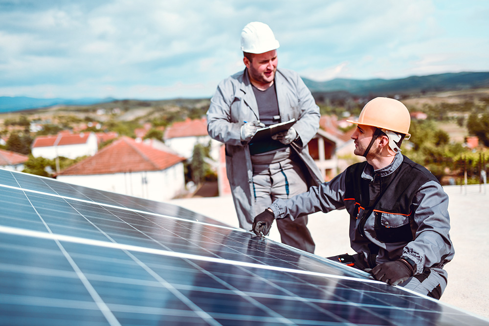 Fachkräfte installieren gemeinsam Photovoltaikmodule auf einem Gebäudedach