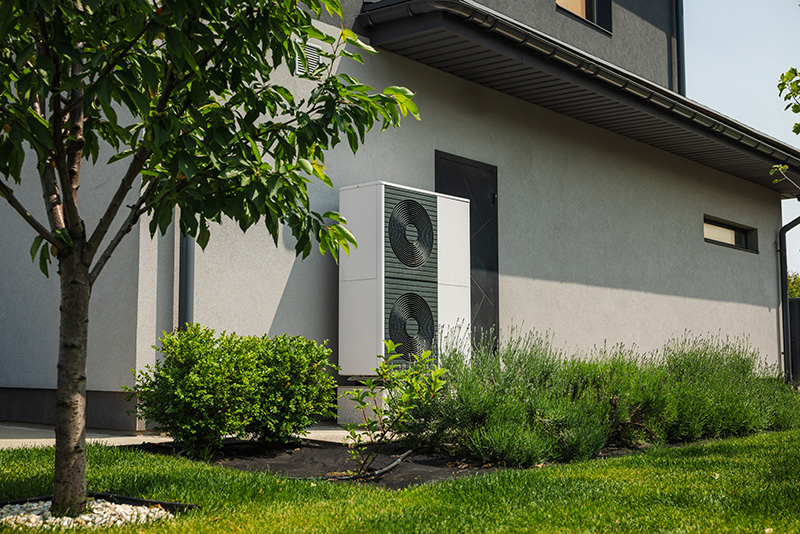 Außeneinheit einer Wärmepumpe neben einem Wohnhaus